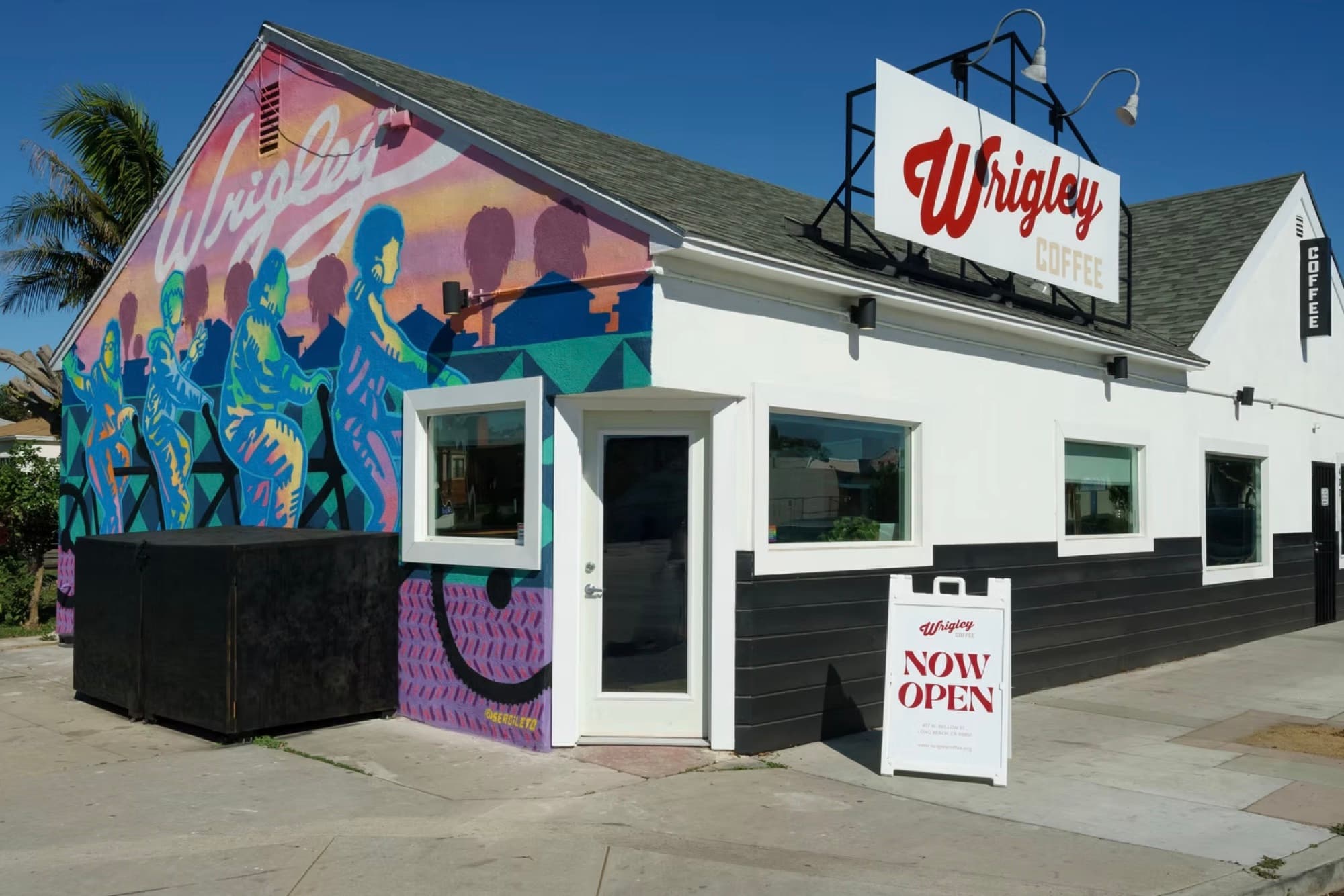 The Wrigley Coffee building, with a bright mural on one wall and a red Wrigley sign on the roof